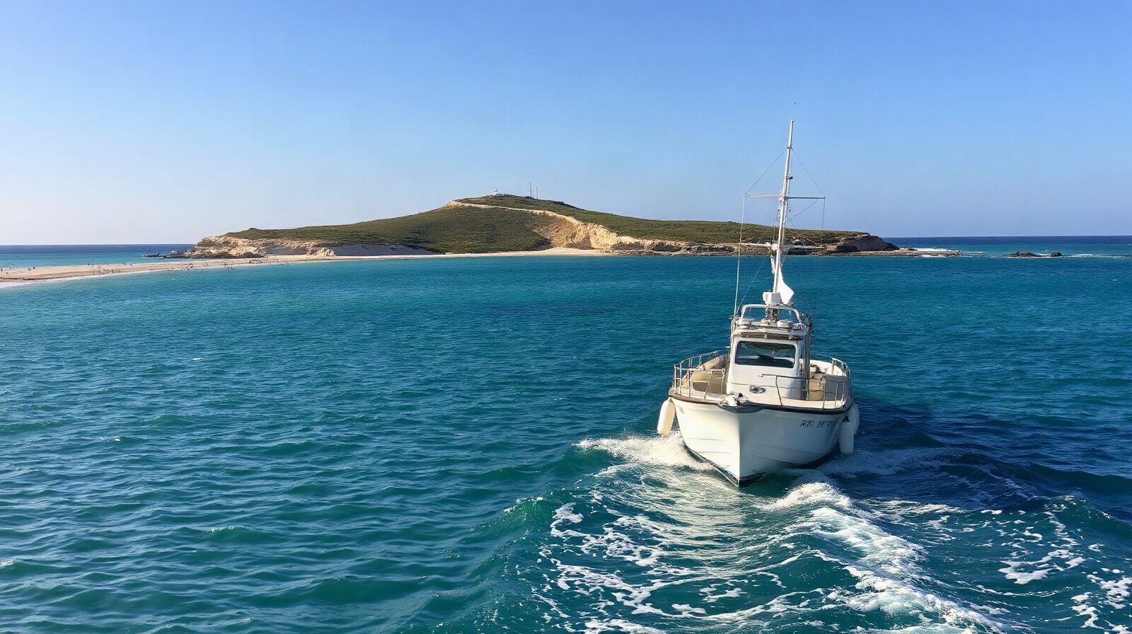 Petit bateau au mouillage devant un îlet, eau claire et fond de sable